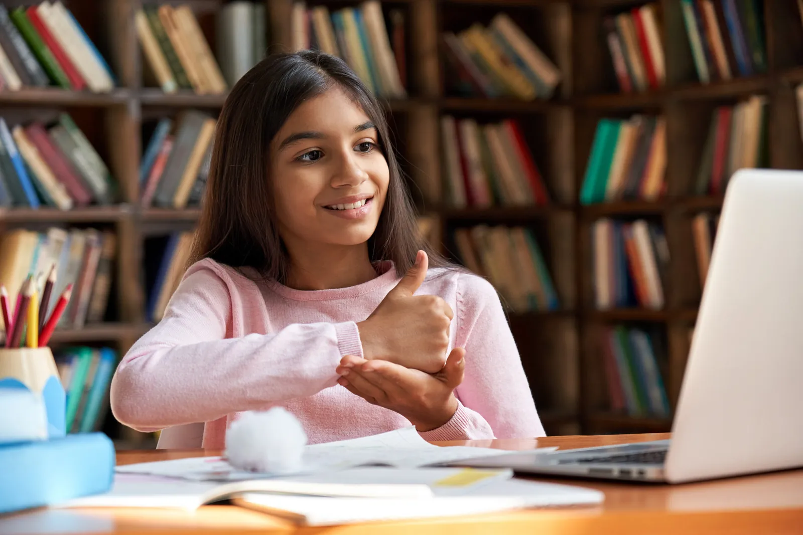 A smiling girl using a laptop in a library