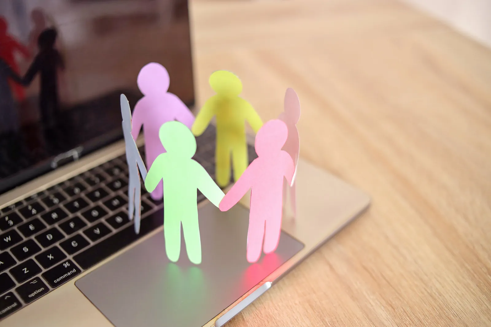 Paper cut-out figures standing on a laptop keyboard