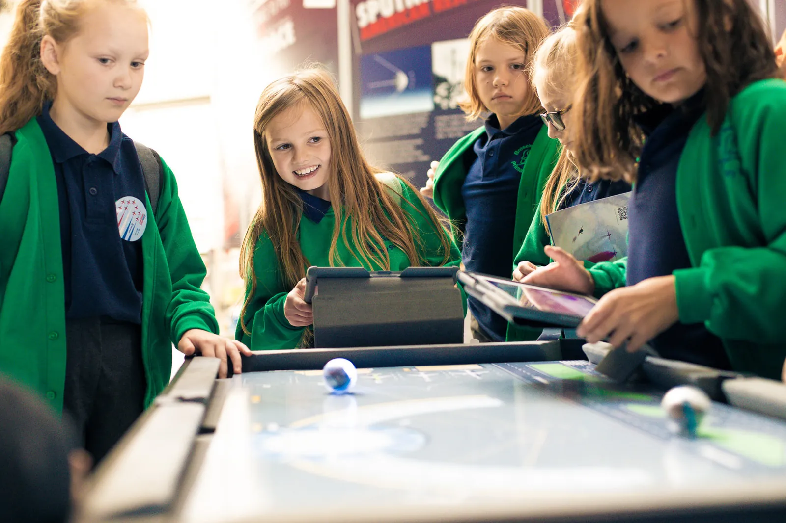 Pupils in green school jumpers working together on a computing project